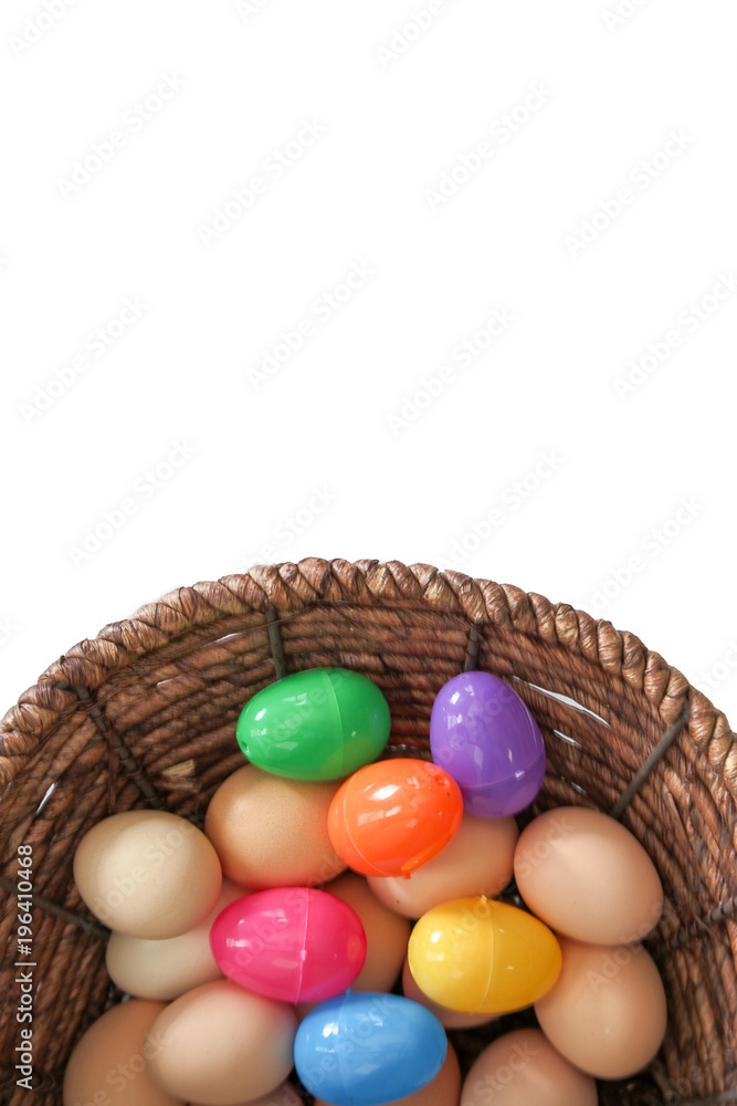 Brown eggs mixed with colorful Easter eggs in a wicker basket isolated pure white background top view shot vertical copy space at top Brown eggs mixed with colorful Easter eggs in a wicker basket isolated pure white background top view shot vertical copy space at top