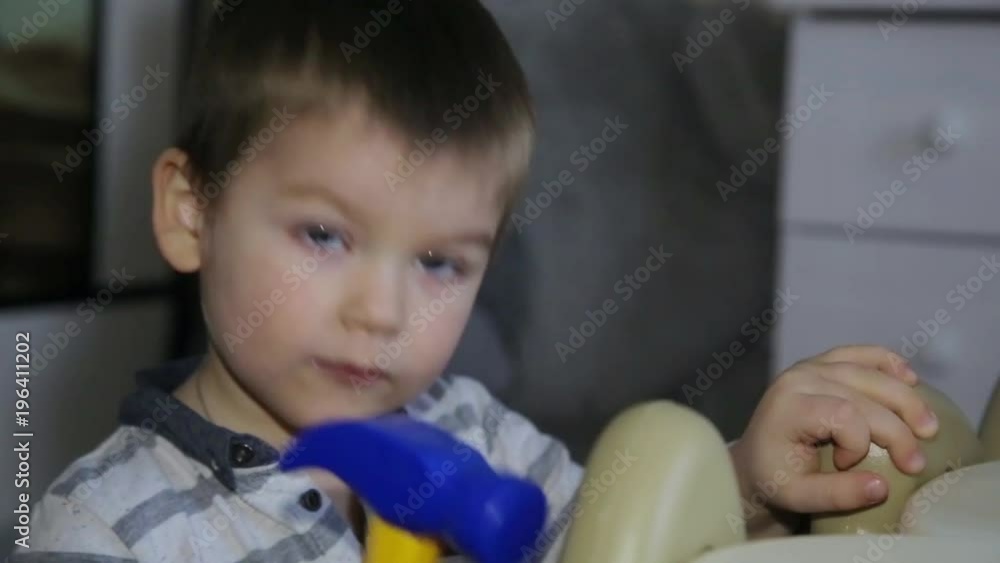 A little boy repairs a table with a toy hammer A little boy repairs a table with a toy hammer