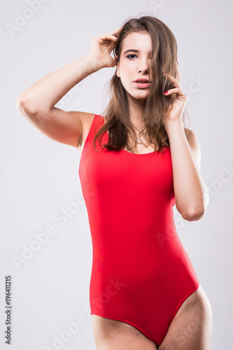 Fashion photo of beautiful and young lady in swimsuits posing in studio on gray © dianagrytsku
