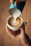 Hand of barista making latte or cappuccino closeup