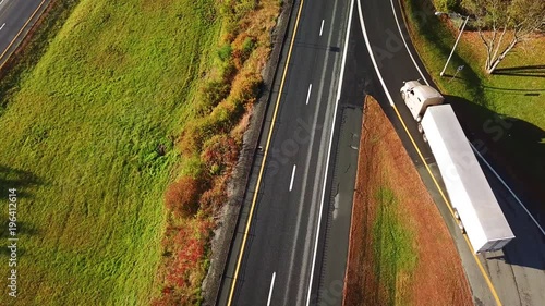 Aerial of a semi truck traveling on a highway road through the fog in fall.
