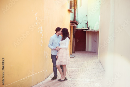 Happy couple hug and tender kiss in tiny street, soft pastel colors sun flare, location Tirana, Albania