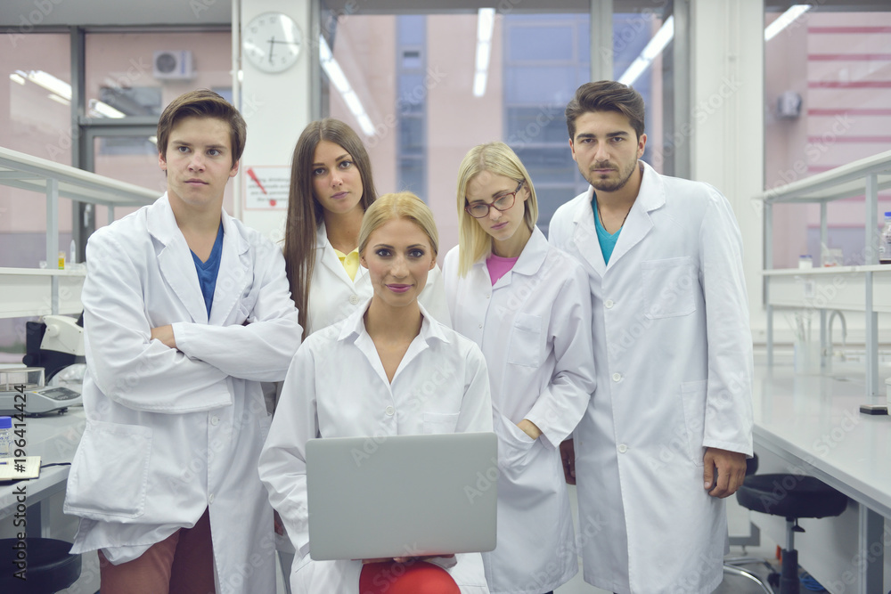 Engineering students meeting and discussing ideas in the laboratory, a student is writing on a whiteboard Engineering students meeting and discussing ideas in the laboratory, a student is writing on a whiteboard