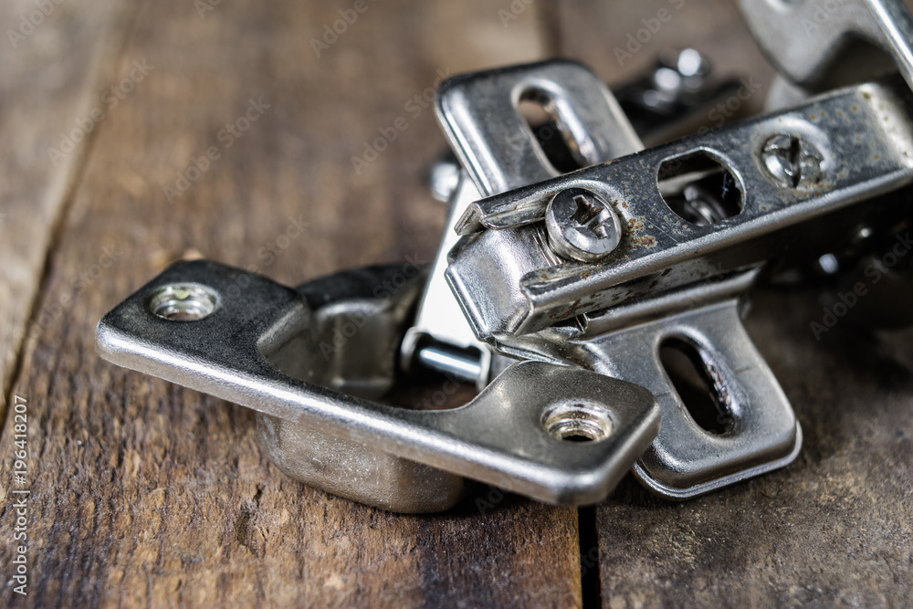 A woodwork hinge on a wooden workshop table. Joinery accessories for the construction of furniture in a carpentry workshop. A woodwork hinge on a wooden workshop table. Joinery accessories for the construction of furniture in a carpentry workshop.