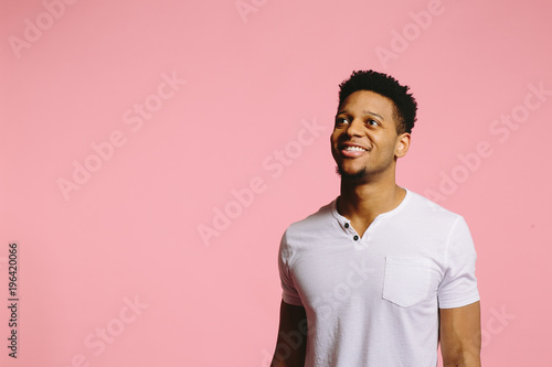 Smiling handsome guy, looking up, on pink background