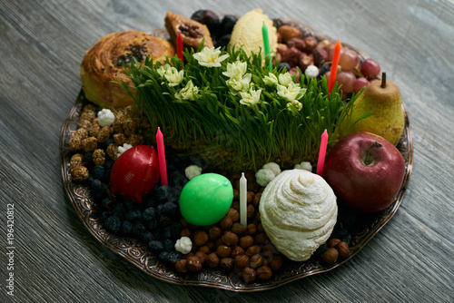 Novruz tray with Azerbaijan national pastry pakhlava   shekerbura  gogal  badambura and dry snacks with green semeni wheat grass on rustic wooden table background