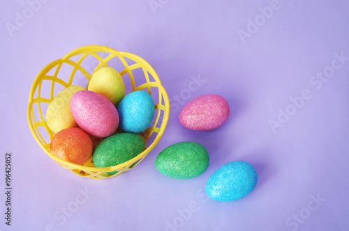 Colorful Easter eggs in basket on purple background