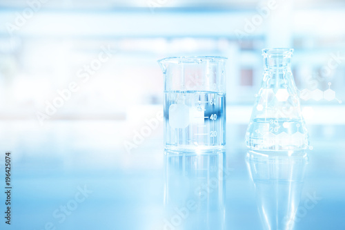 clear blue beaker and flask and chemical structure in research science laboratory background