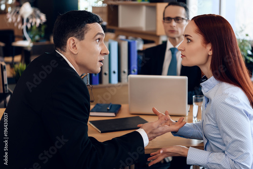 Redheaded woman argues with adult man in divorce lawyer's office.