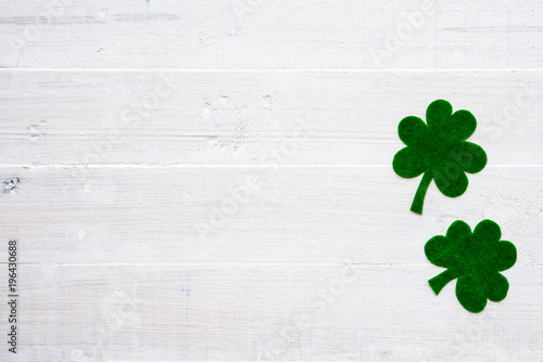 Happy St Patricks Day message on green paper clover and white wooden background