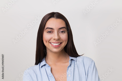Portrait image of smiling Hispanic woman with long hair and blue shirt