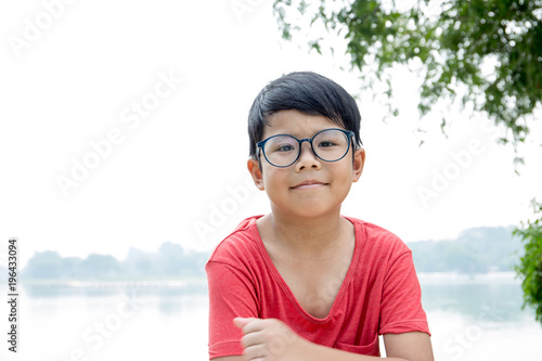 Smiling Asian boy wear red t-shirt cross arms over his chest with pond background