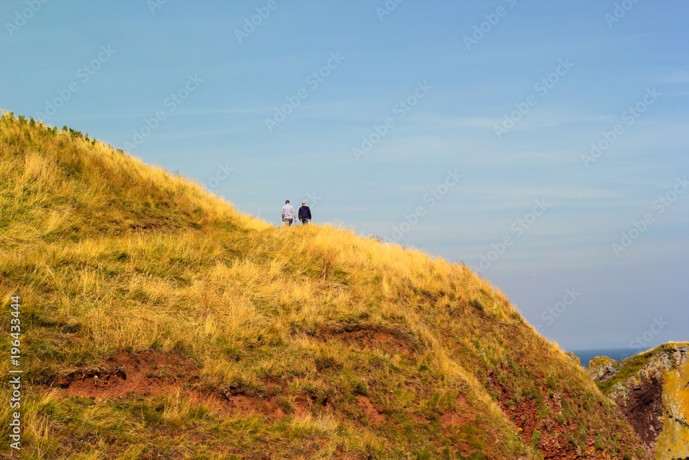 Two tourists walking along beautiful Cliffs of Scotland, St Abb's Head, UK