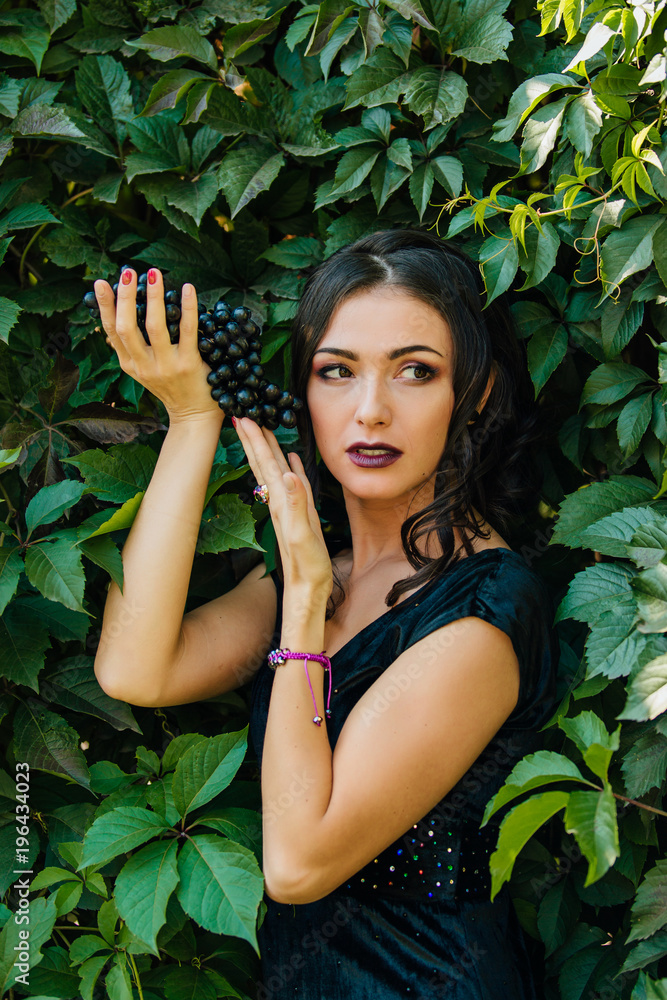 Portrait of young sexy brunette with black grapes. Portrait of young sexy brunette with black grapes.