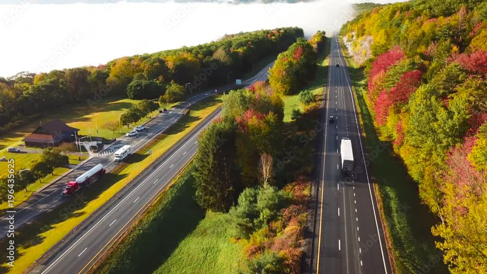 Aerial of a semi truck traveling on a highway road through the fog in fall. Aerial of a semi truck traveling on a highway road through the fog in fall.