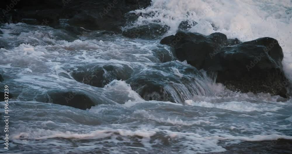 Blue waves roll into the coast of Hawaii in slow motion and break over rocks. Blue waves roll into the coast of Hawaii in slow motion and break over rocks.