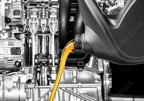 Pouring oil lubricant motor car from bottle on engine background