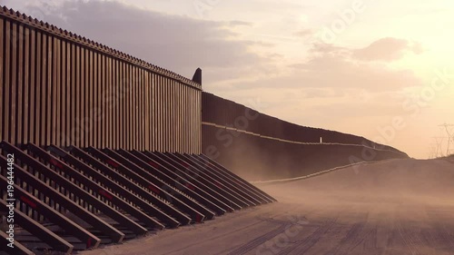 Dust blows at sunset at the border wall at the US Mexico border near Imperial sand dunes, California.