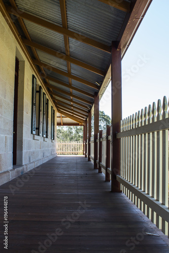 Outdoor verandah patio deck of sandstone brick cottage with picket fence in sunshine © squirrel7707