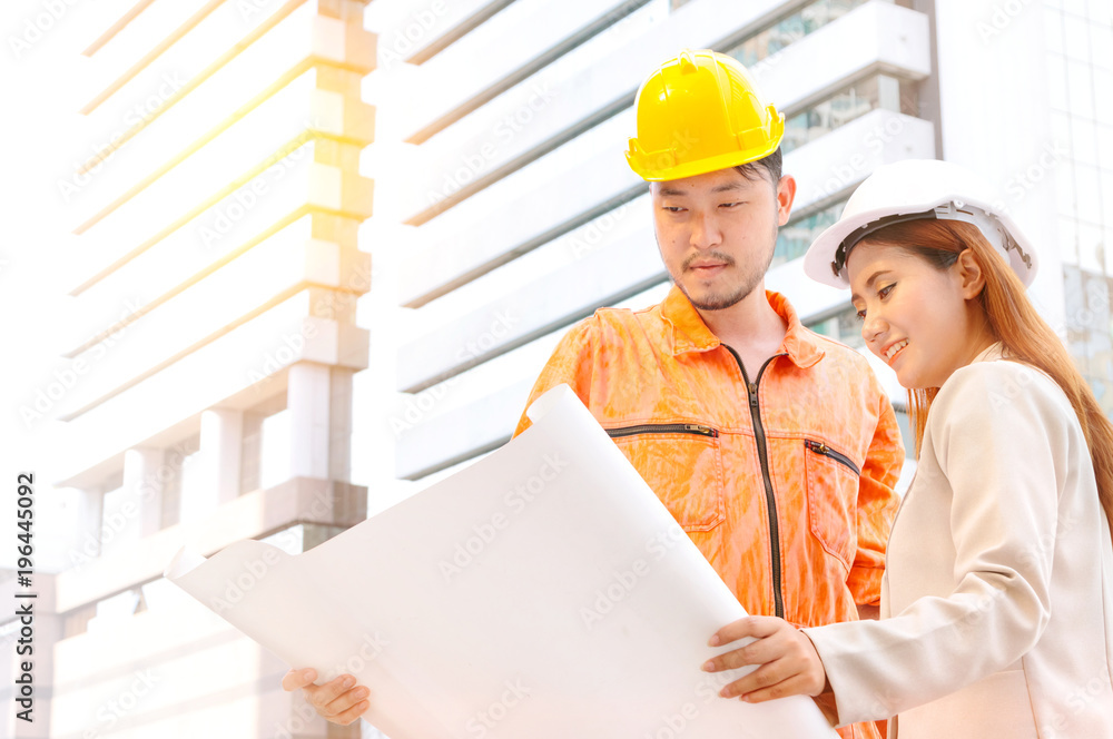 engineer and foreman looking at constructed paper blueprint plans at construction site. engineer and foreman looking at constructed paper blueprint plans at construction site.
