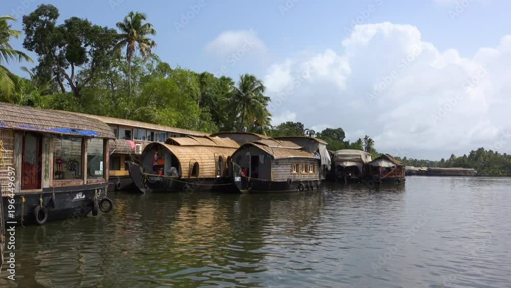 Tourists houseboats line a river in Kerala, India. Tourists houseboats line a river in Kerala, India.