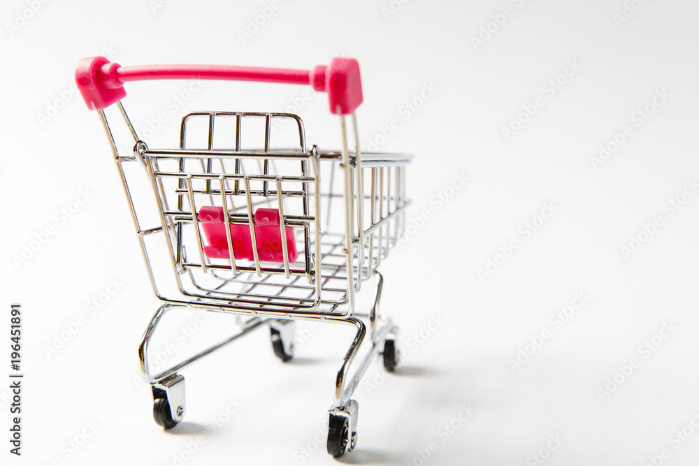 Close up of supermarket grocery push cart for shopping with black wheels and pink plastic elements on handle isolated on white background. Concept of shopping. Copy space for advertisement Close up of supermarket grocery push cart for shopping with black wheels and pink plastic elements on handle isolated on white background. Concept of shopping. Copy space for advertisement