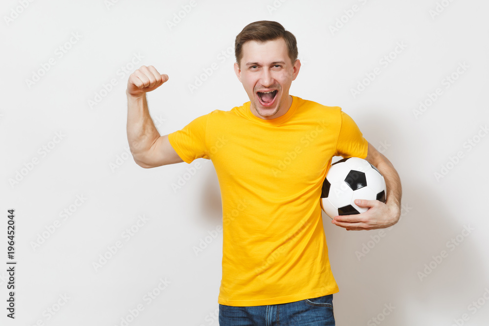 Inspired young European man, fan or player in yellow uniform hold soccer ball, cheer favorite football team, expressive gesticulate hands isolated on white background. Lifestyle concept. Copy space.
