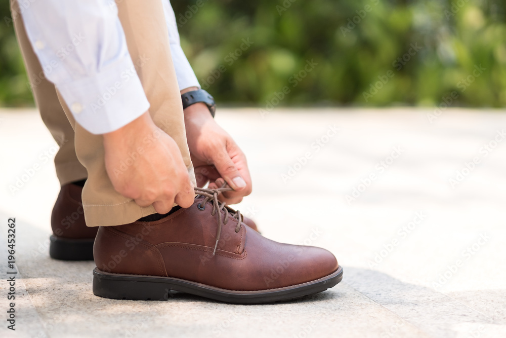 Businessman with leather shoes tying shoe laces, get ready to work or go outside Businessman with leather shoes tying shoe laces, get ready to work or go outside