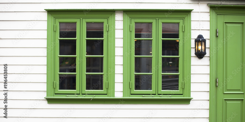 Casa blanca de madera con puerta y ventana verdes