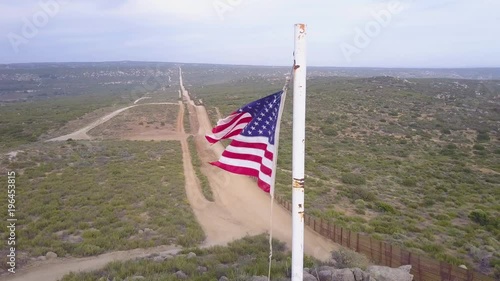 The American flag flies over the U.S. Mexico border wall in the California desert. photo