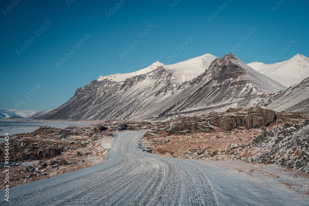 Beautiful View and winter landscape of Iceland's golden circle road during the sunset with the snow-capped mountain as a background and the road asphalt as a foreground. Beautiful View and winter landscape of Iceland's golden circle road during the sunset with the snow-capped mountain as a background and the road asphalt as a foreground.
