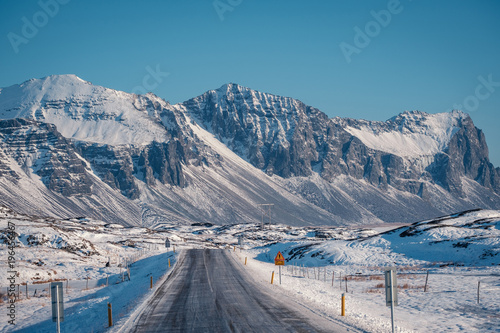 Canvastavla Beautiful View and winter landscape of Iceland's golden circle road during the sunset with the snow-capped mountain as a background and the road asphalt as a foreground