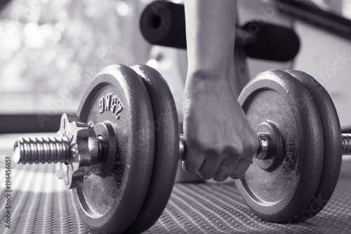 black and white image of women hand lifting the steel dumbbell in a gym musclebuilding