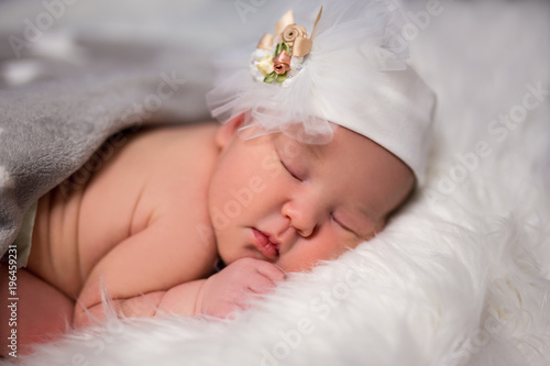 close up of cute sleeping baby in hat over white