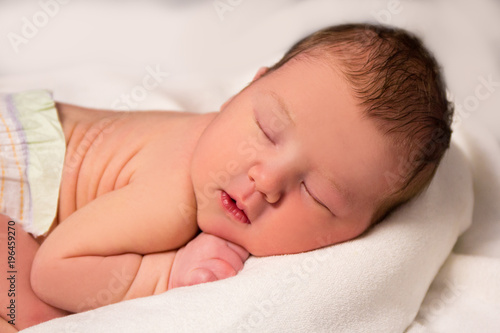 close up of cute sleeping newborn baby over white blanket