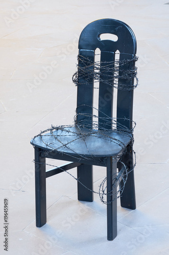 Black chair wrapped in barbed wire photo