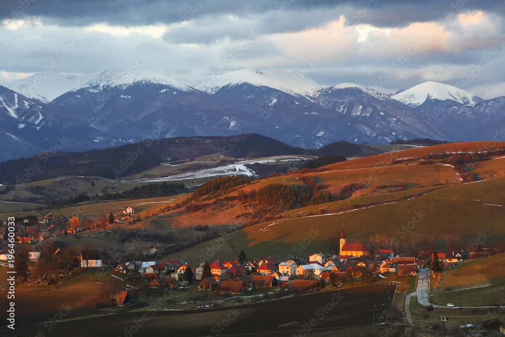 Village in Turiec region with view of Mala Fatra mountain range in winter.
