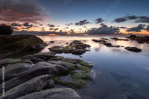 Serinity view of sunset seascape with natural coastal rocks on the beach. Long expose lead to soft focus on the image.