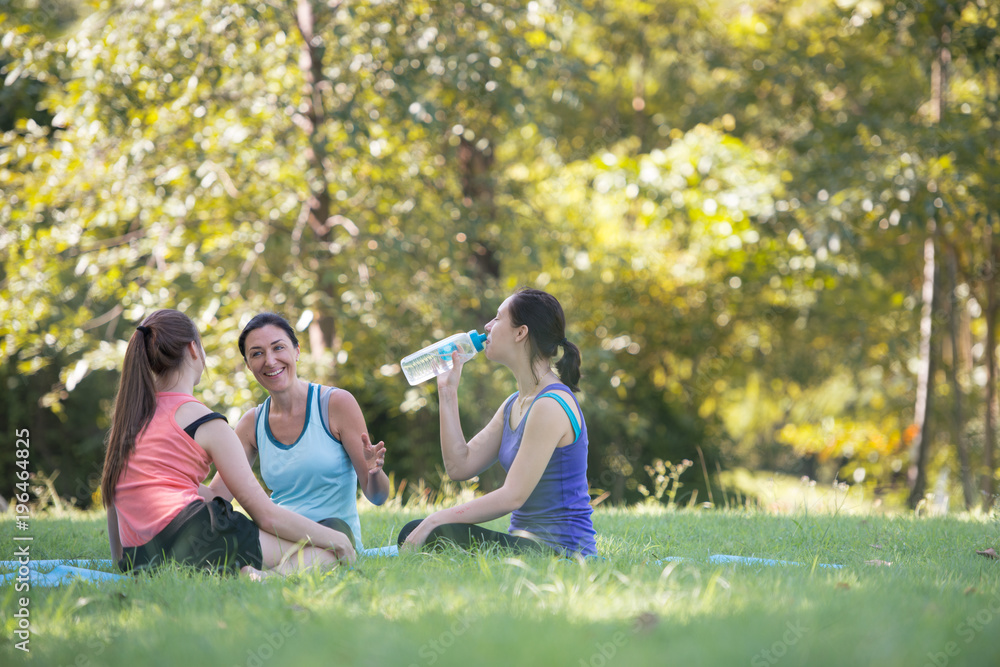 Families with young Russian mother and daughter are talk about exercise and Drink Water. After practice yoga at the park finished. Health and Fitness concept Families with young Russian mother and daughter are talk about exercise and Drink Water. After practice yoga at the park finished. Health and Fitness concept