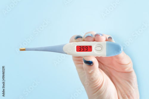 Electronic thermometer in a female hand. Elevated body temperature. Close up
