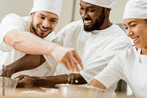 laughing group of baking manufacture workers kneading dough together