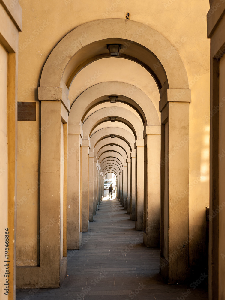 Obraz premium Passageway in Florence with round arches and person at the end