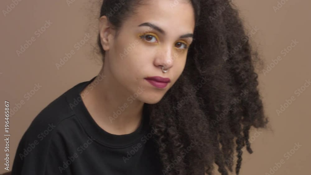 closeup woman's portrait in studio in beige background Curly hair mixed race woman closeup woman's portrait in studio in beige background Curly hair mixed race woman