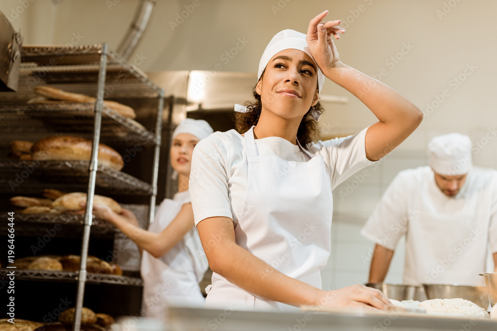 happy and tired female baker working at baking manufacture