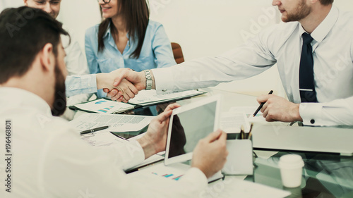 handshake business partners after discussing the terms of a contract in the workplace in the office.