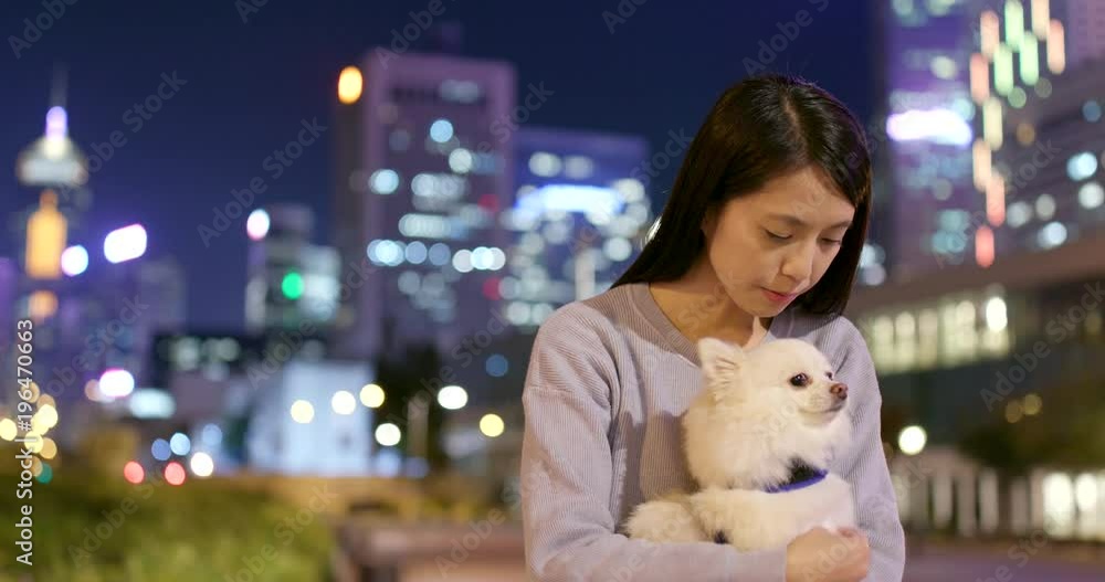 Woman playing with her dog in city at night Woman playing with her dog in city at night