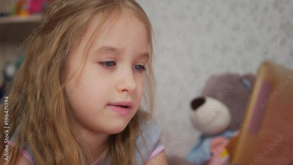 Small girl with tablet computer on the sofa at the children's room Small girl with tablet computer on the sofa at the children's room