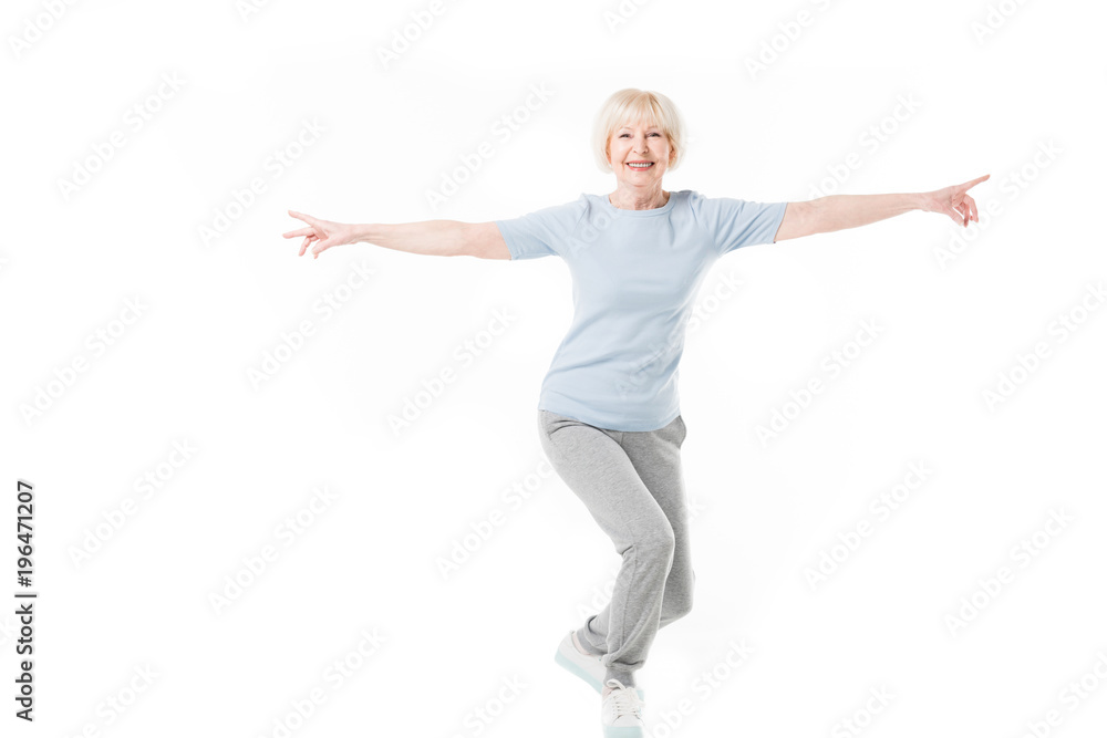 Smiling senior sportswoman standing with wide arms isolated on white Smiling senior sportswoman standing with wide arms isolated on white