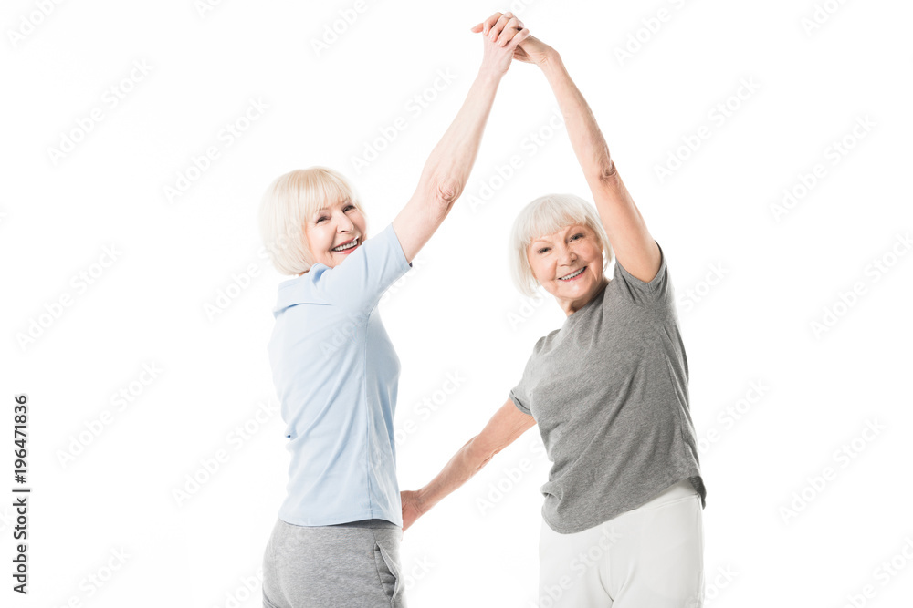 Two smiling senior sportswomen doing exercise isolated on white Two smiling senior sportswomen doing exercise isolated on white