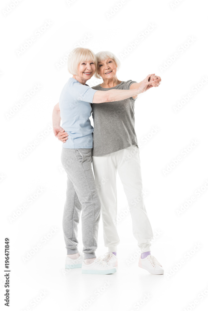 Two senior sportswomen doing exercise isolated on white Two senior sportswomen doing exercise isolated on white